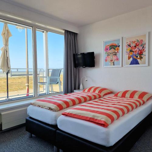 a hotel room with two beds and a large window at Hotel B&B Seahorse in Katwijk
