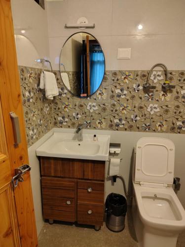 a bathroom with a sink and a toilet and a mirror at The sky walk in Manāli