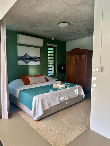 a bedroom with a large bed with green walls at Cosy Studio 71 in Petite Case Noyale