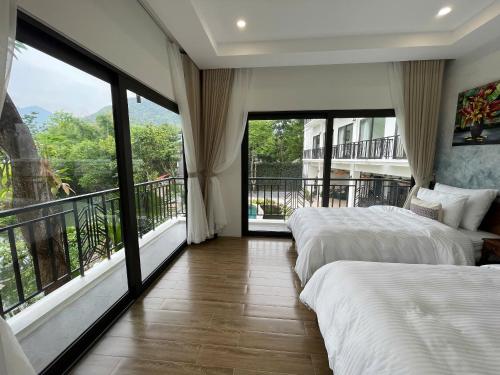 a bedroom with two beds and a balcony with large windows at Mai Châu Home in Mai Châu