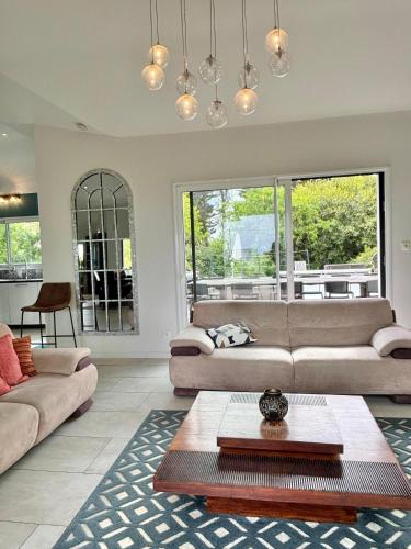 a living room with two couches and a table at Villa des Abers vue mer, GR34, piscine chauffée in Landéda