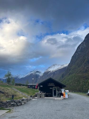 a building with a snow covered mountain in the background at Olden Camping in Olden