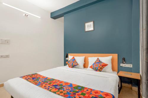 a bedroom with a bed with a blue wall at Fabhotel Namaskar - Nr Udayagiri and Khandagiri caves in Bhubaneshwar