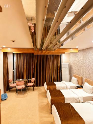 a hotel room with four beds and a table and chairs at Ward Hotel Basra in Al Başrah