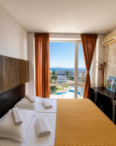 a bedroom with a large bed and a large window at Atlantis Resort Sea View in Burgas