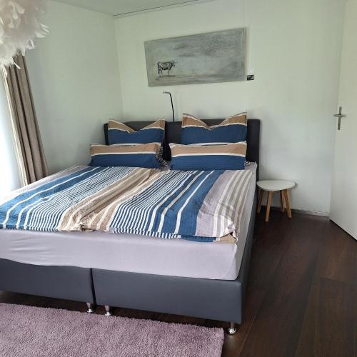 ein Schlafzimmer mit einem Bett mit blau-weißen Kissen in der Unterkunft Sandras Flat in Giswil