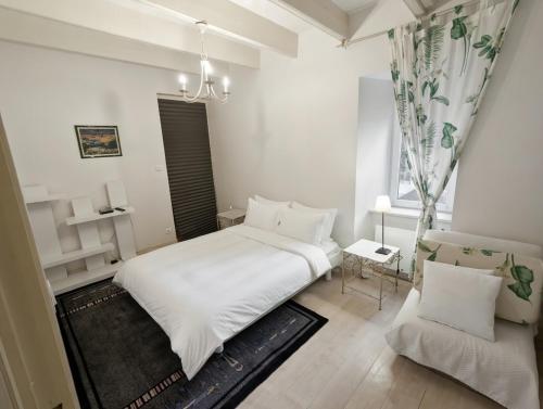 a white bedroom with a bed and a chair at Appartement cosy - au cœur du bourg in Crozon