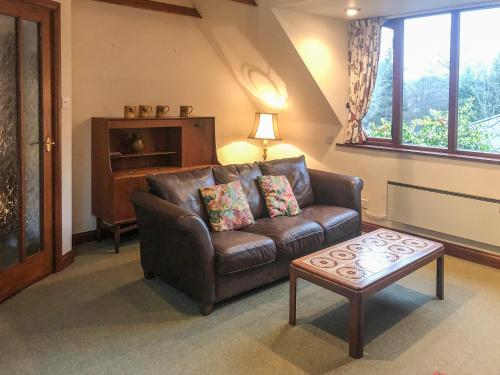 a living room with a leather couch and a coffee table at Forge Mill Cottage in Dalbeattie