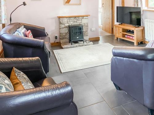 a living room with two leather chairs and a fireplace at Stocks Tree Cottage in Preston Wynne