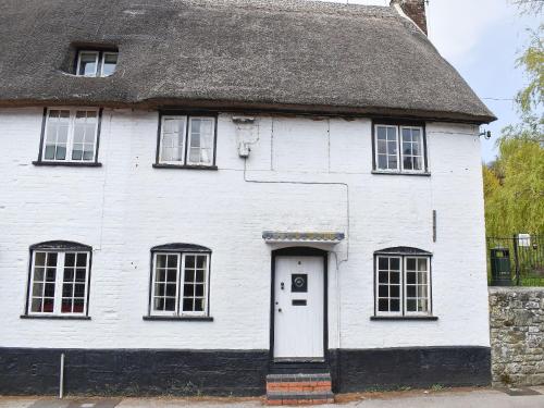 an old white house with a thatched roof at St James Cottage in Shaftesbury