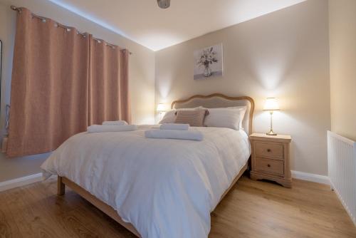 a bedroom with a large white bed and a night stand at Coolbuck Cottage in Lisbellaw