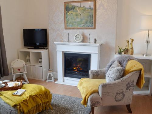 a living room with a fireplace and a chair at Sonny Cottage in Glanamman