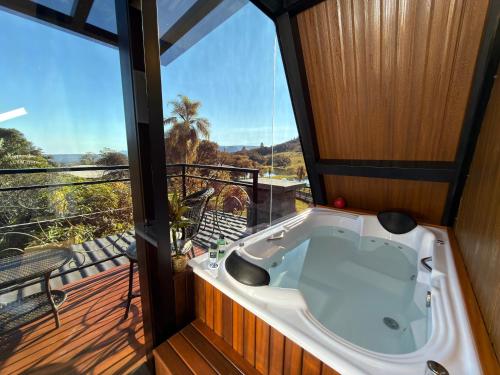 a jacuzzi tub in a room with a balcony at Cabana Silêncio das Pedras in Três Coroas