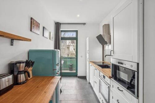 a kitchen with white cabinets and a blue refrigerator at Arbio I Modern Apart near Leipzig Stötteritz in Leipzig