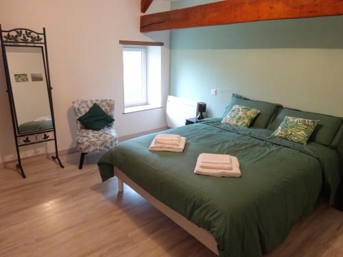 a bedroom with a green bed with two towels on it at Le Cottage de Paul et Angéline in Boismé