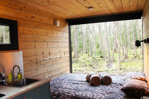 a bedroom with a bed with a view of a forest at PRIVAATNE Metsamajake SAUNAGA "KOHIN" in Sigula