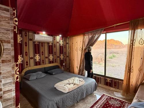 a bedroom with a bed and a large window at Rayyan Bedouin life camp in Wadi Rum