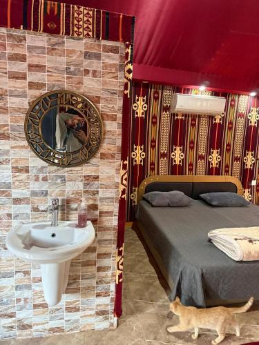 a bathroom with a sink and a bed and a mirror at Rayyan Bedouin life camp in Wadi Rum