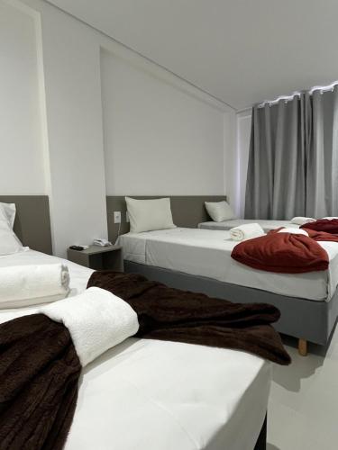 a room with three beds with towels on them at Areiao Park Hotel in Goiânia