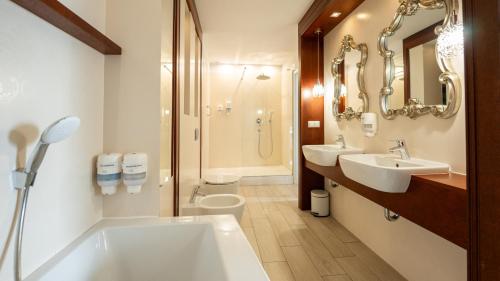 a bathroom with two sinks and a toilet and a shower at Biały Dom Henlex Hotel Restauracja in Poznań