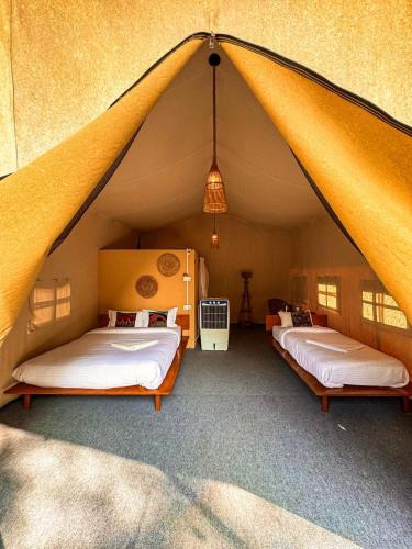 a bedroom with two beds in a tent at Hotel Tharu Garden in Sauraha