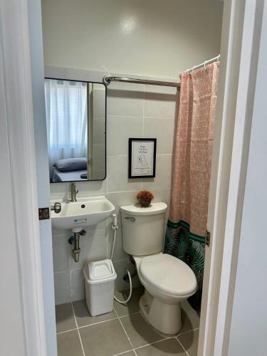 a bathroom with a toilet and a sink and a mirror at TWD 716 Cityscape in Bacolod