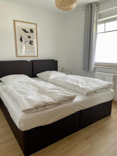 a bed with white sheets and a black frame in a bedroom at Ferienwohnung H 25 "Tausendschön" in Graal-Müritz