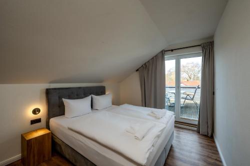 a bedroom with a white bed with a large window at Johouse Zingst Johouse Zimmer 15 in Zingst