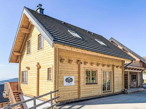 a small wooden house with a black roof at Chalet Nockhütte by Interhome in Hochrindl