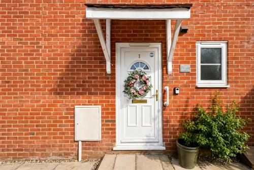 a brick house with a white door with a wreath on it at Central Brockenhurst Village Flat with Free Parking in Brockenhurst