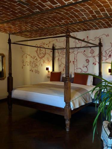 a bedroom with a canopy bed with red flowers on the wall at Relais Conac 1888 - Luxury B&B - Adults Only in Castelnuovo Don Bosco