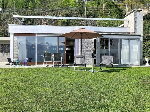 a house with two chairs and an umbrella in the grass at Villa Villa Bikini by Interhome in Saint-Gingolph