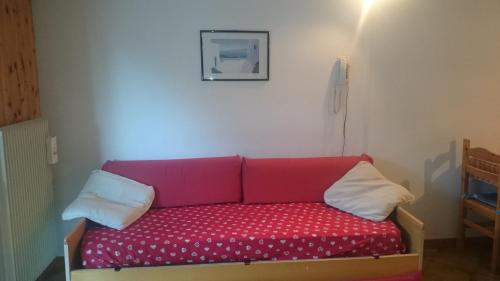 a red couch in a room with two pillows at Rododendro Apartment in Passo San Pellegrino