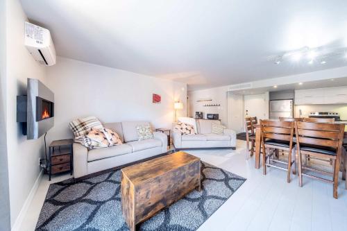 a living room with a couch and a table at Modern Condo with Pool - Le Rendez-Vous in Beaupré