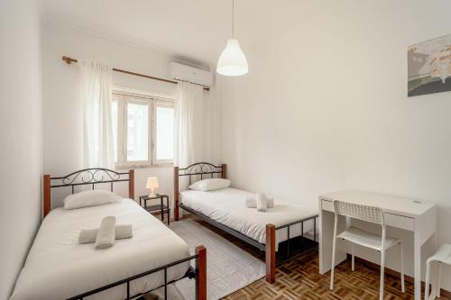 two beds in a room with a desk and a table at Almada Central by Homing in Almada