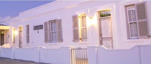 a white building with windows and a white fence at River Bend Cottages in Graaff-Reinet