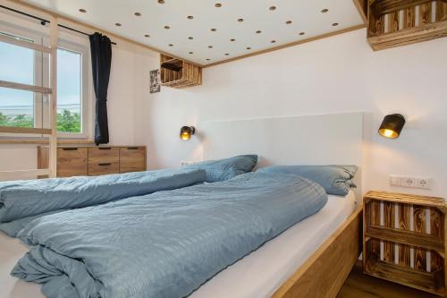 a bedroom with a large bed with blue sheets at Tiny Haus 2 - Feige in Kressbronn am Bodensee