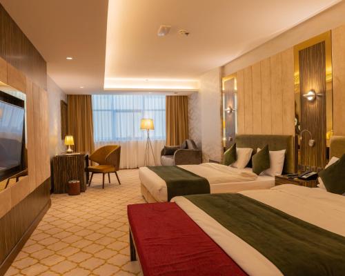 a hotel room with two beds and a flat screen tv at Royal Crown Muscat in Muscat