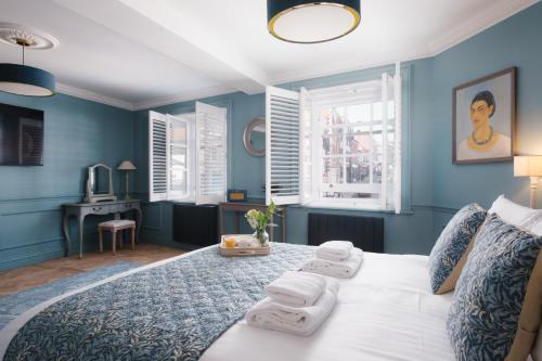 a blue bedroom with a bed with towels on it at Lowcross House in Whitchurch