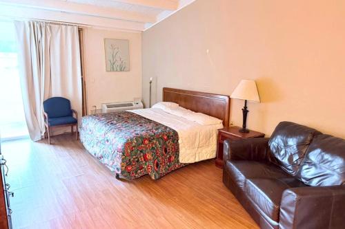 a bedroom with a bed and a leather couch at Campus Inn by Hotel O Gainesville - University Area in Gainesville