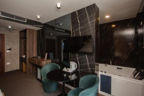 ein Hotelzimmer mit Tisch, Stühlen und Fernseher in der Unterkunft Hotel Chicago in Shkodra