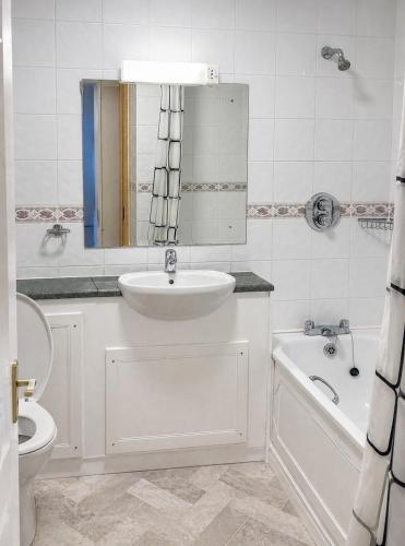 a bathroom with a sink and a toilet and a tub at Blue Water House in Bundoran