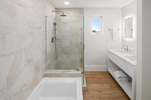 a white bathroom with a shower and two sinks at Alexandra Resort - All-Inclusive in Providenciales