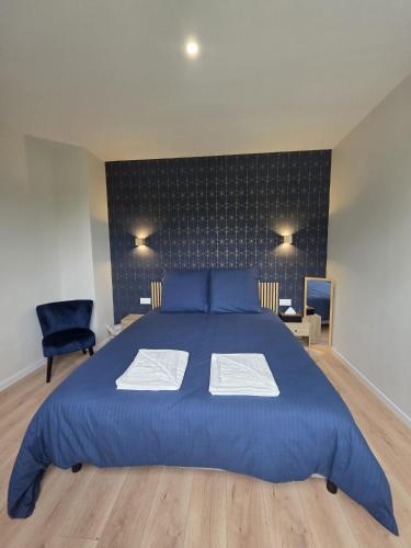 a bedroom with a large blue bed and a chair at Doré in Carhaix-Plouguer