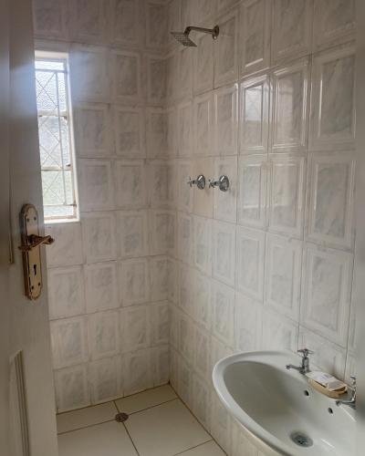 a white bathroom with a tub and a sink at Green Oasis Lodges in Harare
