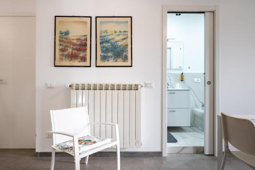 a white room with three paintings on the wall and a white chair at Il Cortile Holiday House in Caccamo