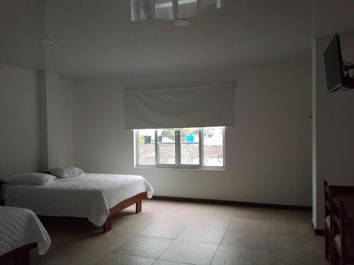 a bedroom with two beds and a window at Hotel Nayarith in Acacías