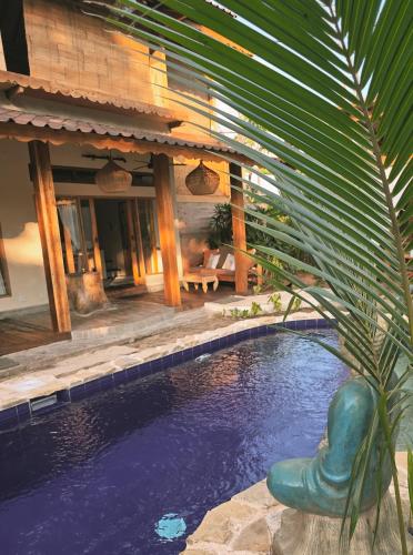 ein Pool vor einem Haus mit einer Palme in der Unterkunft Gili Matiki, Resort & Private Villa in Gili Air