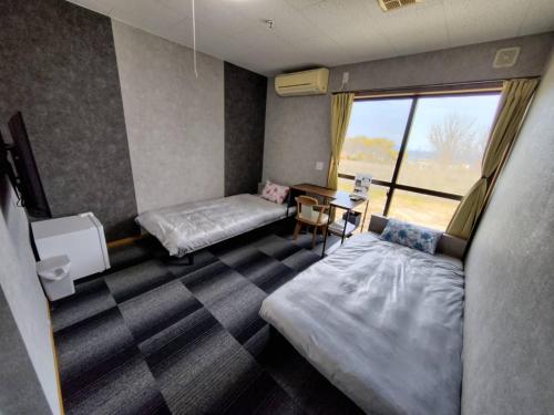 a room with two beds and a table and a window at 五島宿Seina in Goto