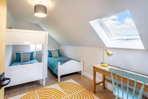 a attic bedroom with a bunk bed and a desk at The Roost in Wendling